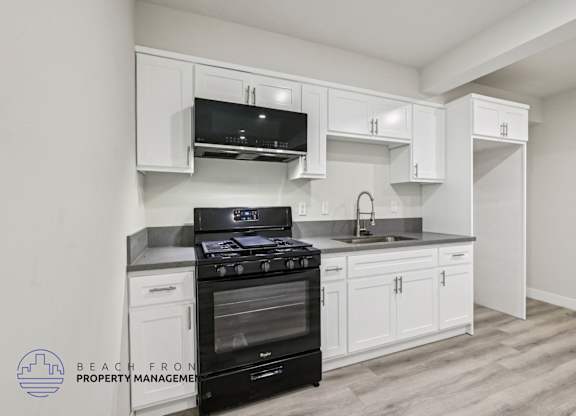 A kitchen with white cabinets and a black stove top oven.