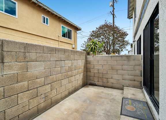 A tan house with a brown brick wall and a black mat in front.