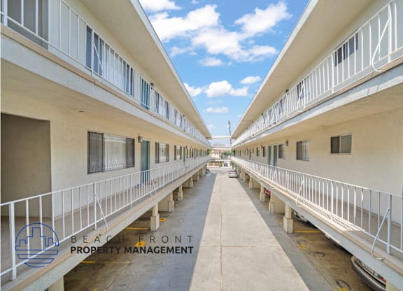 an empty corridor between two apartment buildings with white railings