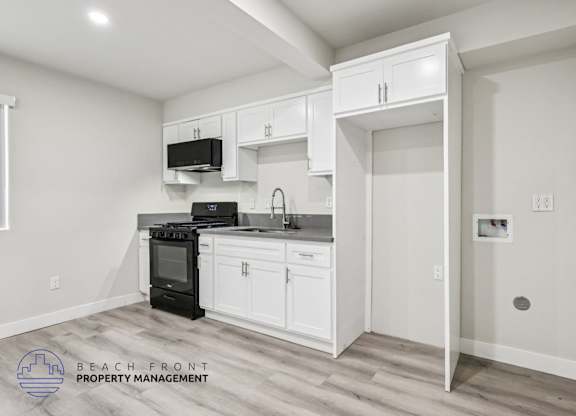 A kitchen with white cabinets and a black stove top oven.