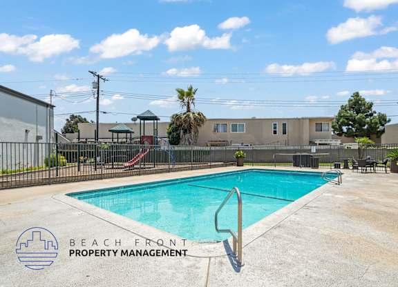 A pool with a slide and a building in the background.