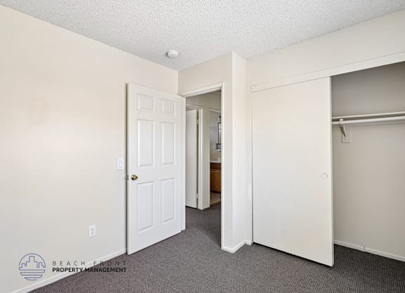 A room with a white door and a white closet with a shelf.