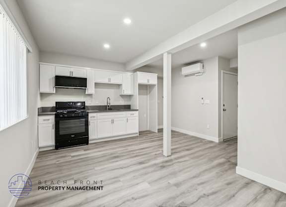 A spacious kitchen with white cabinets and a black stove top oven.
