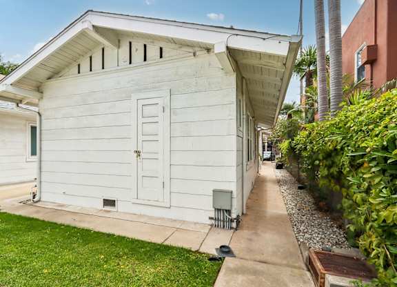 A white wooden house with a green door and windows.