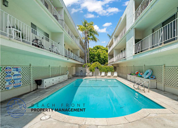 A pool in the middle of a courtyard surrounded by white buildings.