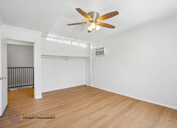 A room with a ceiling fan and wooden flooring.
