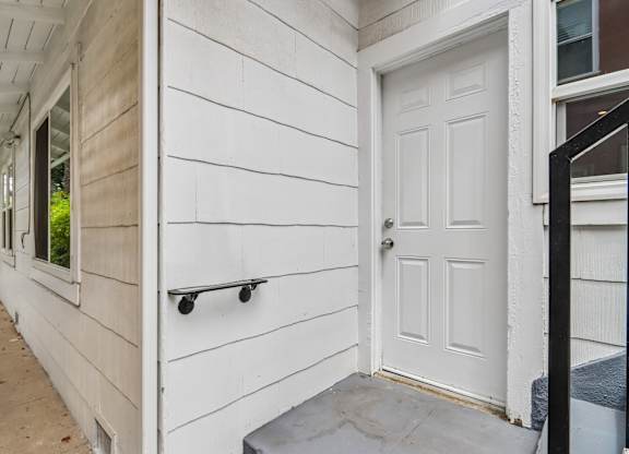 A white door is on the right side of a white wall.