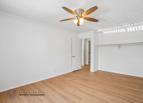 A room with a ceiling fan and wooden flooring.