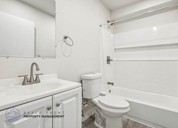 A white bathroom with a toilet, sink, and bathtub.