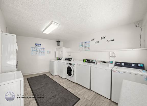 A laundry room with washers and dryers and a sign that says Beach Front Property Management.