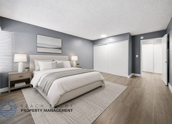 A well-lit bedroom with a large bed and a nightstand with a lamp.