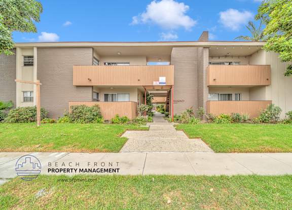 A building with a lawn in front and a sign for Beach Front Property Management.
