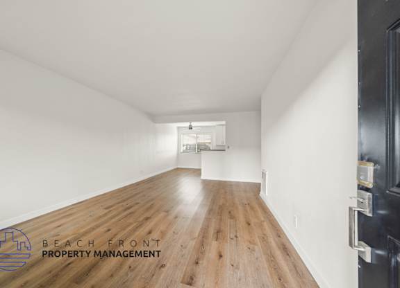 A long, empty hallway with a logo for Beach Front Property Management in the bottom left corner.