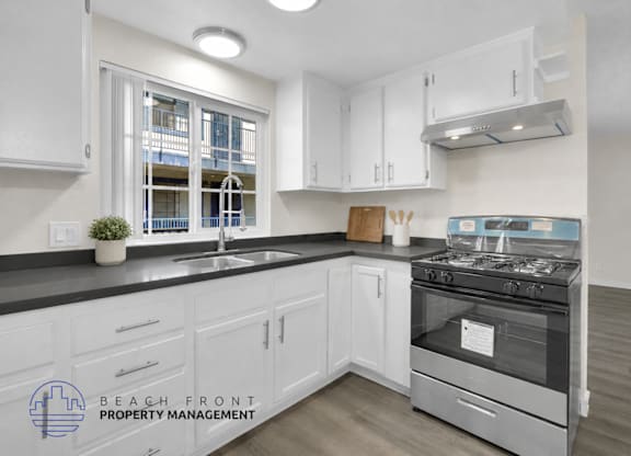 A kitchen with white cabinets and a stove top oven.