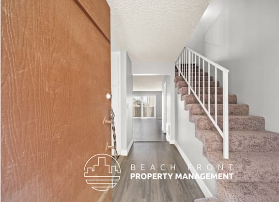 a view of the hallway of a house with stairs and a hallway with a door