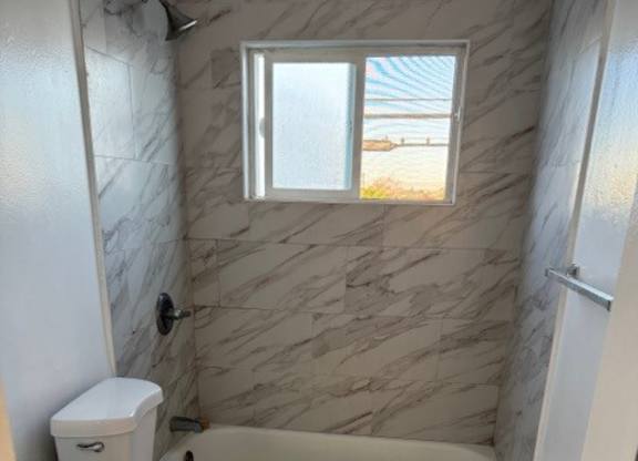 A bathroom with a tub, toilet and sink.