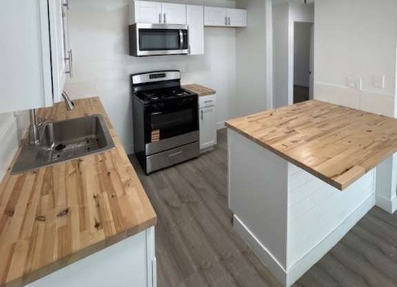 A kitchen with a wooden counter top and a white fridge.