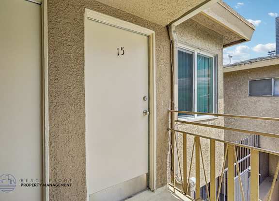 A balcony with a white door and a window with a blue curtain.