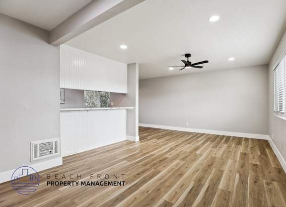 A spacious room with wooden flooring and a ceiling fan.