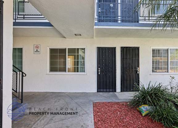 A white building with a black door and a no parking sign on the wall.