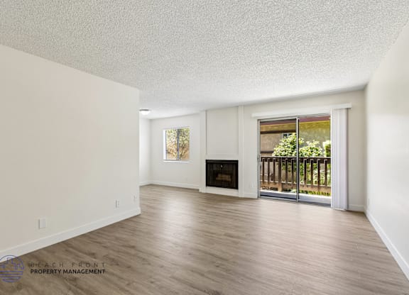 A spacious living room with a fireplace and sliding glass doors leading to a balcony.
