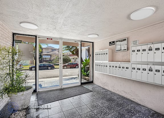 A view of a parking garage with a glass door and a wall of mailboxes.