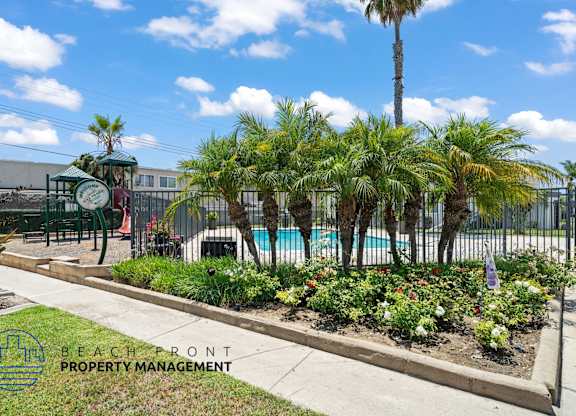 A pool area with a fence and a sign that says Beachfront Property Management.