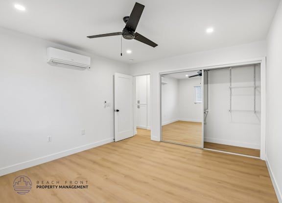A room with a ceiling fan and a sliding glass door leading to a balcony.