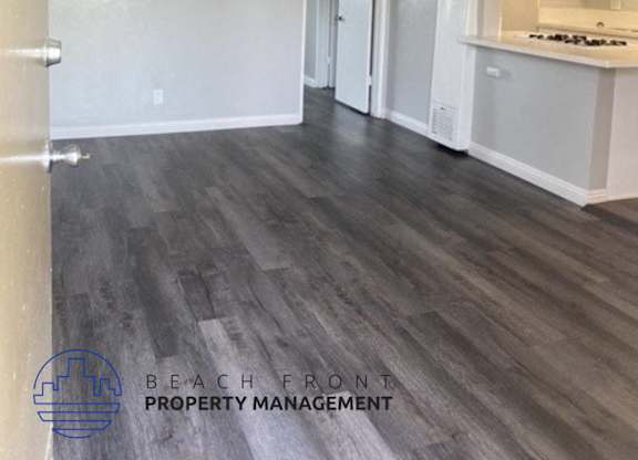 an empty living room and kitchen with wood floors