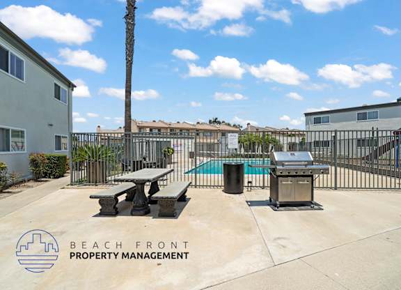 A pool area with picnic tables and a grill is managed by Beach Front Property Management.