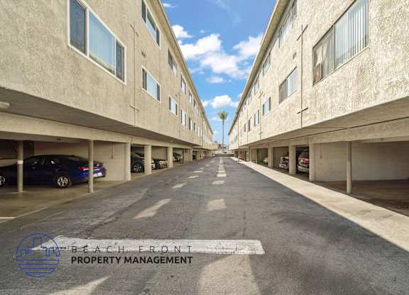 A long, empty parking garage with a logo for Beach Front Property Management in the bottom left corner.