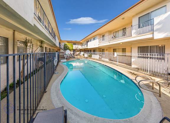 A swimming pool in a residential area surrounded by a fence.