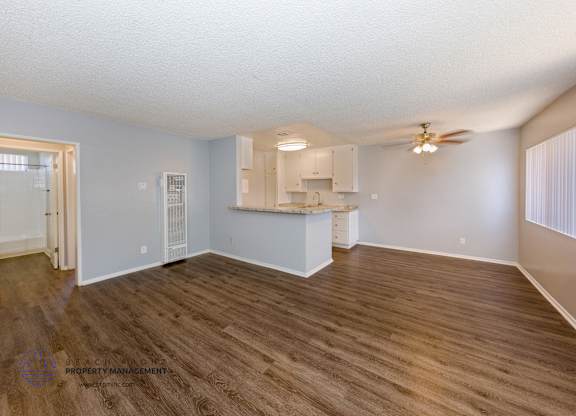 A spacious room with wooden flooring and a ceiling fan.
