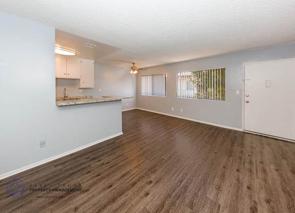 A spacious room with wooden flooring and white walls.