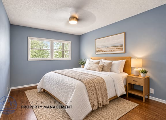 A bedroom with a bed, nightstand, and a painting on the wall.