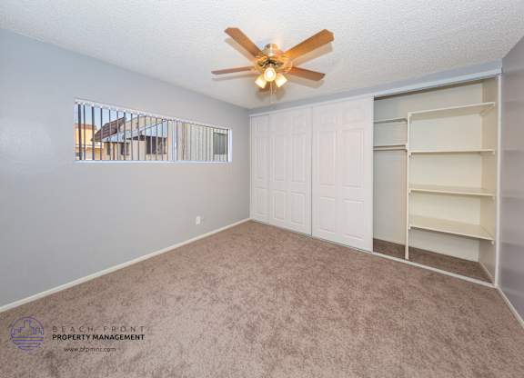 A room with a fan and a window overlooking a balcony.