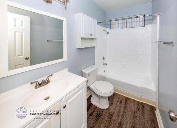 A white bathroom with a toilet, sink, and shower.