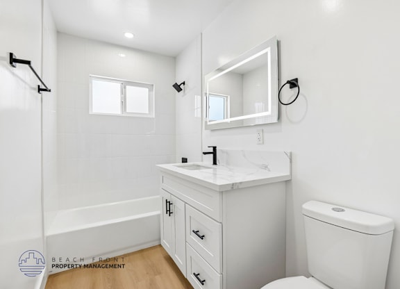 A white bathroom with a toilet, sink, and mirror.