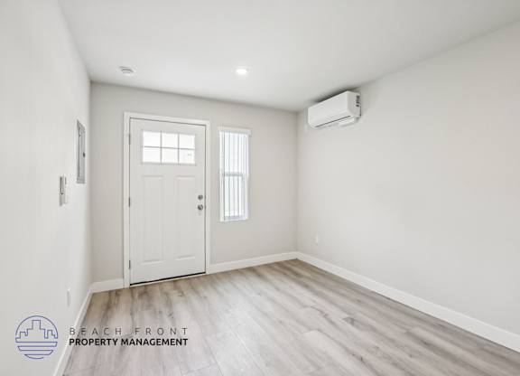 A room with a white door and a window with blinds, and a logo for Beach Front Property Management.
