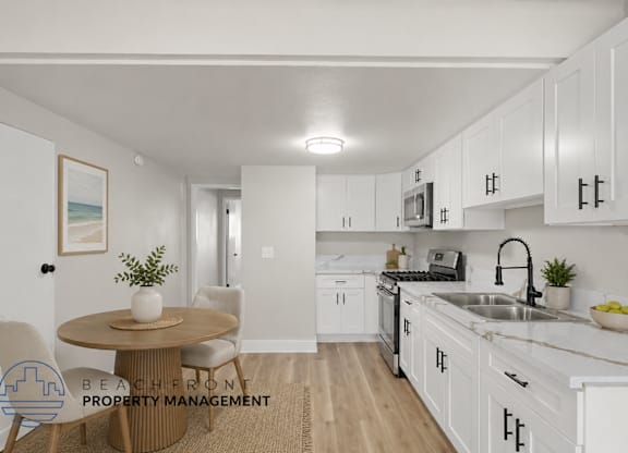 A kitchen with white cabinets and a round table with chairs.
