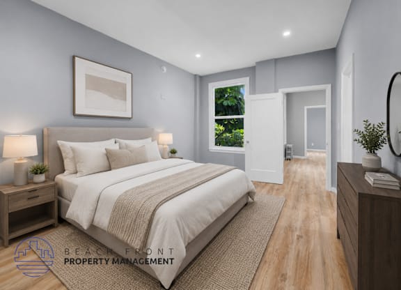 A well-lit bedroom with a large bed and a view of the outdoors through a window.