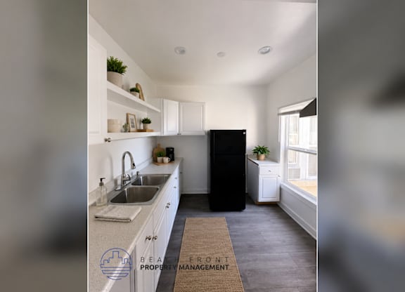 A kitchen with a sink, a refrigerator, and a window.