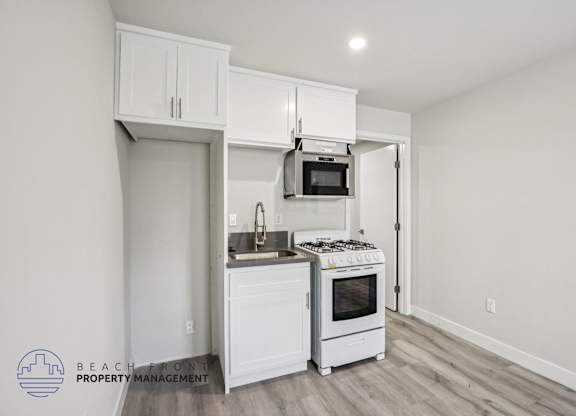 A kitchen with white cabinets and a stove top oven.