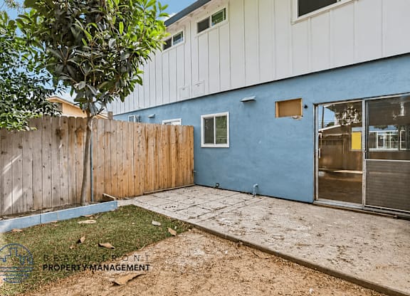 A blue building with a wooden fence and a tree in front.