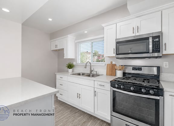 A kitchen with white cabinets and a stove top oven.