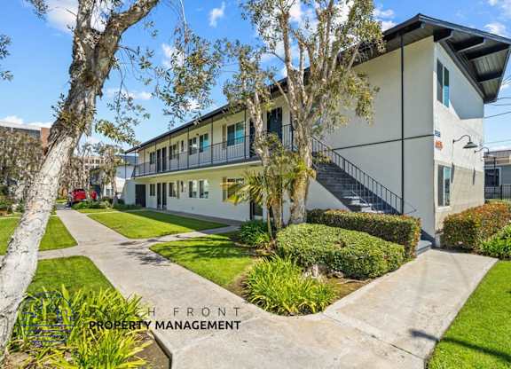 a large white building with a sidewalk and trees in front of it