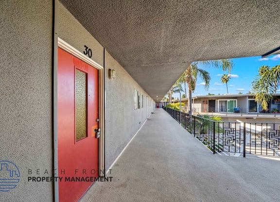 A red door with the number 30 on it is on the left side of a concrete wall.