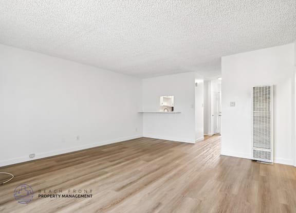 A spacious room with wooden flooring and white walls.