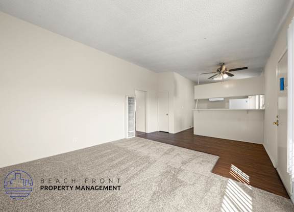 A spacious room with a carpeted floor and a ceiling fan.