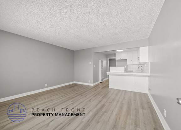 A room with wooden flooring and a logo for Beach Front Property Management.